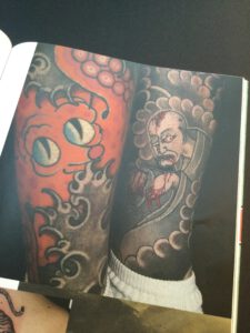 Two tattooed men’s calf’s showing an Octopus and a Japanese ghost.