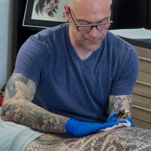 Rick Wilson Tattooing big dragon across a mans back.