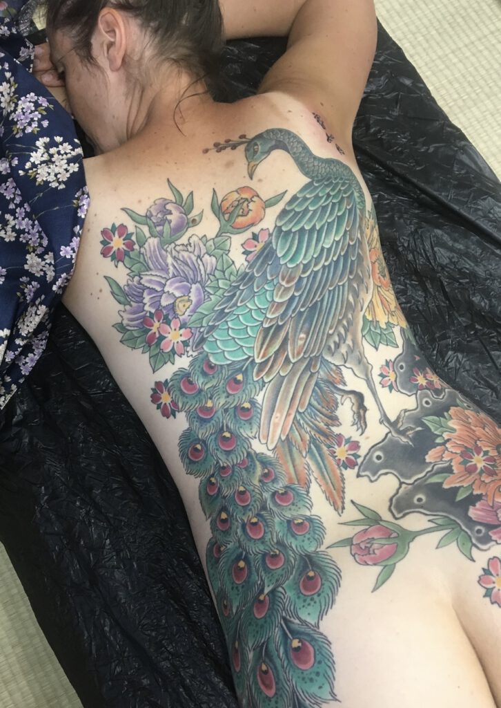 Women tattooed with Peacock across the back.