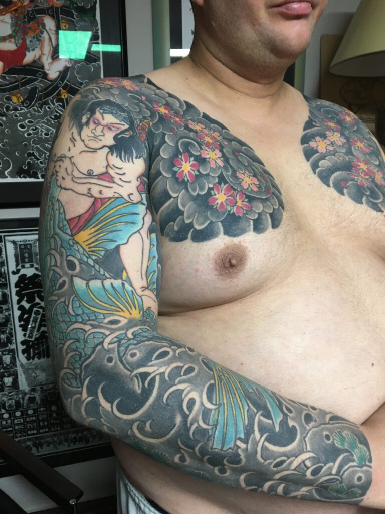 Japanese Hero "Asahina Yoshihide" struggling with river monster, tattooed on mans Arm and Chest. Including cherry Blossom and background.