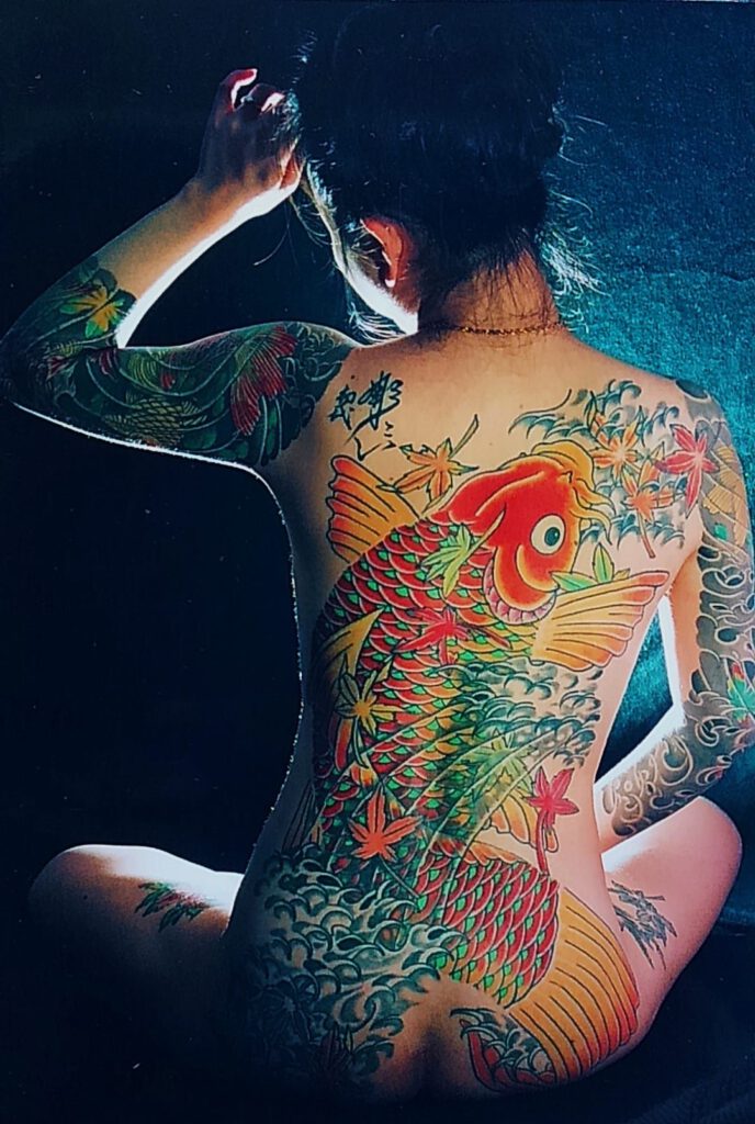 Womens back covered with Koi and maple leaves. Tattooed Women.