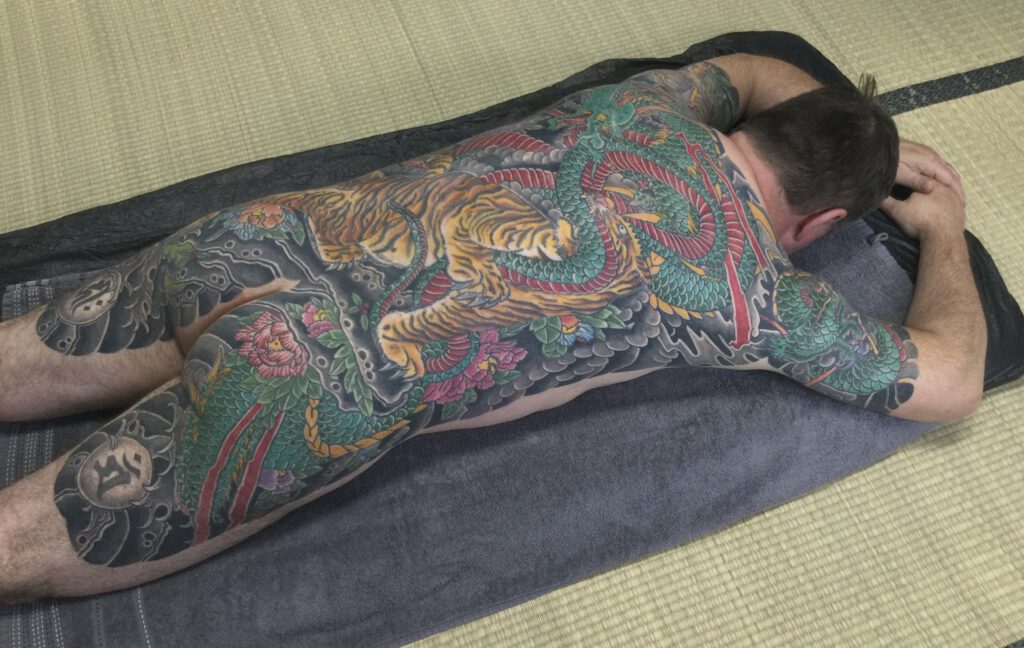Tiger and Dragon battle tattooed across mans back.Backpiece tattoos are common in Japan.