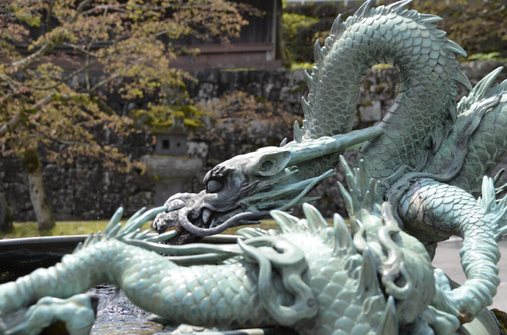 side view of a Bronze Dragon Fountain in Nikkō, with trees in the background.
At Toshogu-ji temple. 