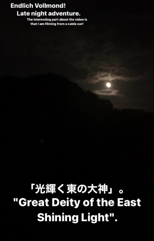 Full moon over Japan. The majority of the picture is black, being the mountain silhouette. then rapidly opening to a soft grey. the moon shining on surrounding clouds make the picture perfect.