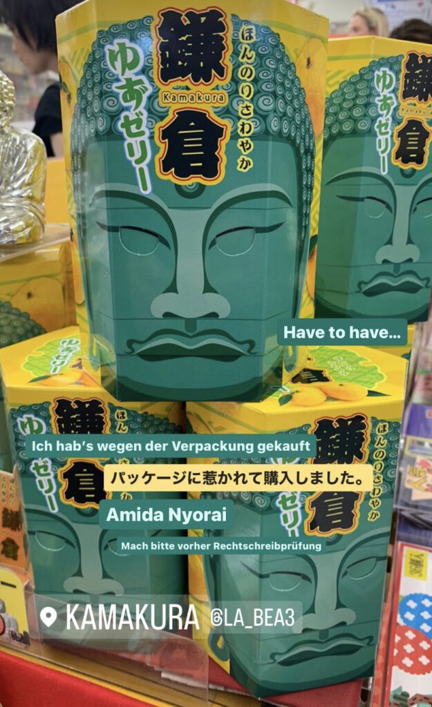 Sweets with taste of orange friut in a hexagon shaped box. The box being decorated like the head of the statue "Great Buddha of Kamakura" in mint with yellow background. When lifting the head to take a sweet the eyes open and the mouth does the same. Many boxes staked on top of each other to encourage the buyer.
