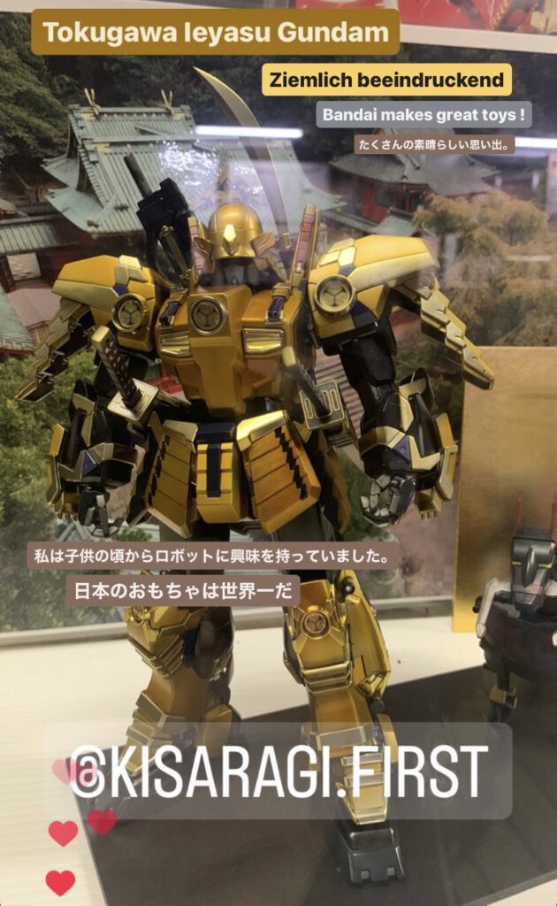 Golden yellow Gandam Robot figure of Tokugawa Leyasu with details like family crest on the chest, arms and leg joints. A foto of the shrine in the background make it almost real.