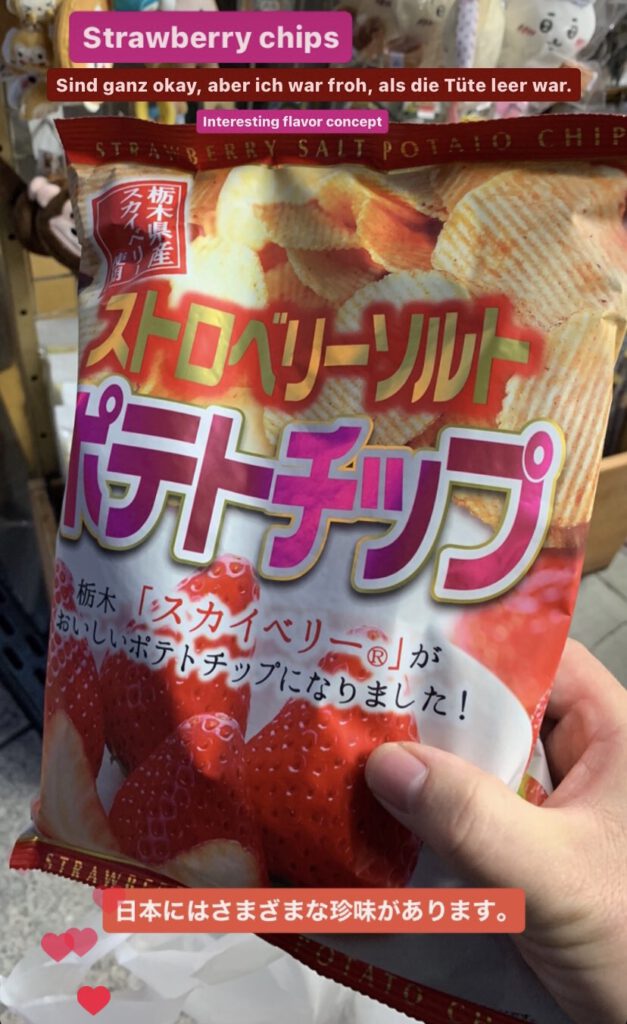Hand holding a bag of strawberry flavoured crisps. The bag designed with crisps on the top and strawberries to be seen on the bottom. The transition being filled with golden lettering surrounded with yellow. Magenta Katakana lettering. Only in Japan.