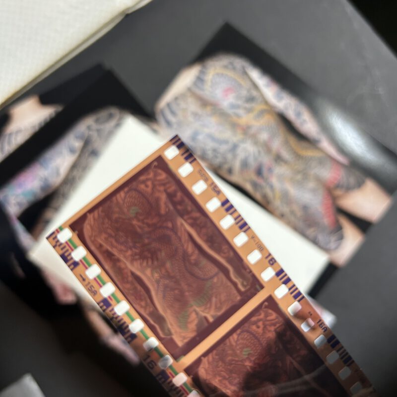 A slide of a Foto Negativ showing a dragon on a mans back. The picture of the dragon slightly hidden under the negativ strip.