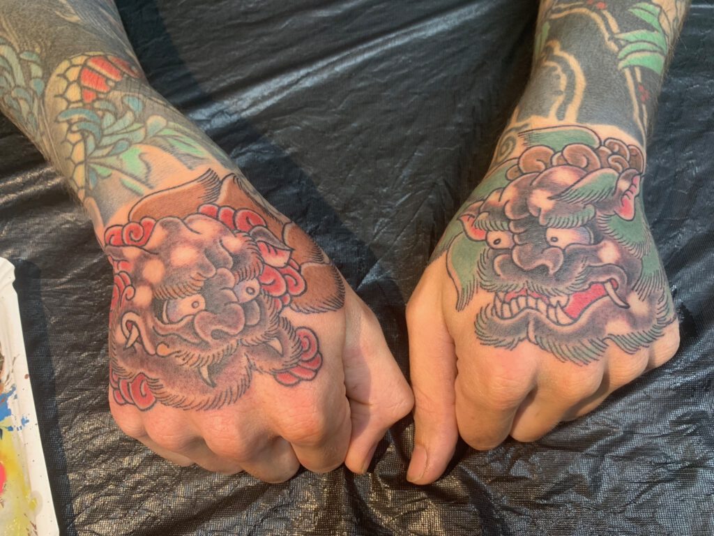 A female Chinese Llon (called "Shishi" in Japan) head tattooed on the right hand. The left hand depicts the male head. Of course this includes that the correct colours for each sex are used. Together they repesent teamwork!