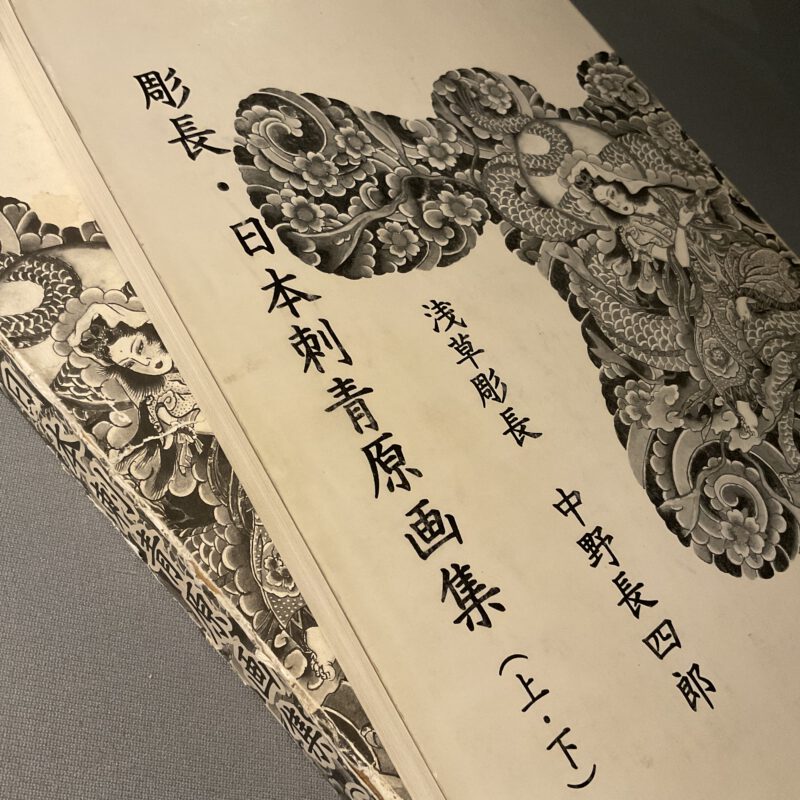 Buch in schwarz/Weis ungefähr DinA3 Format. Japanische Schrift Zeichen und Bilder einer weiblichen Gottheit aus dem Shintoismus sind zu sehen.